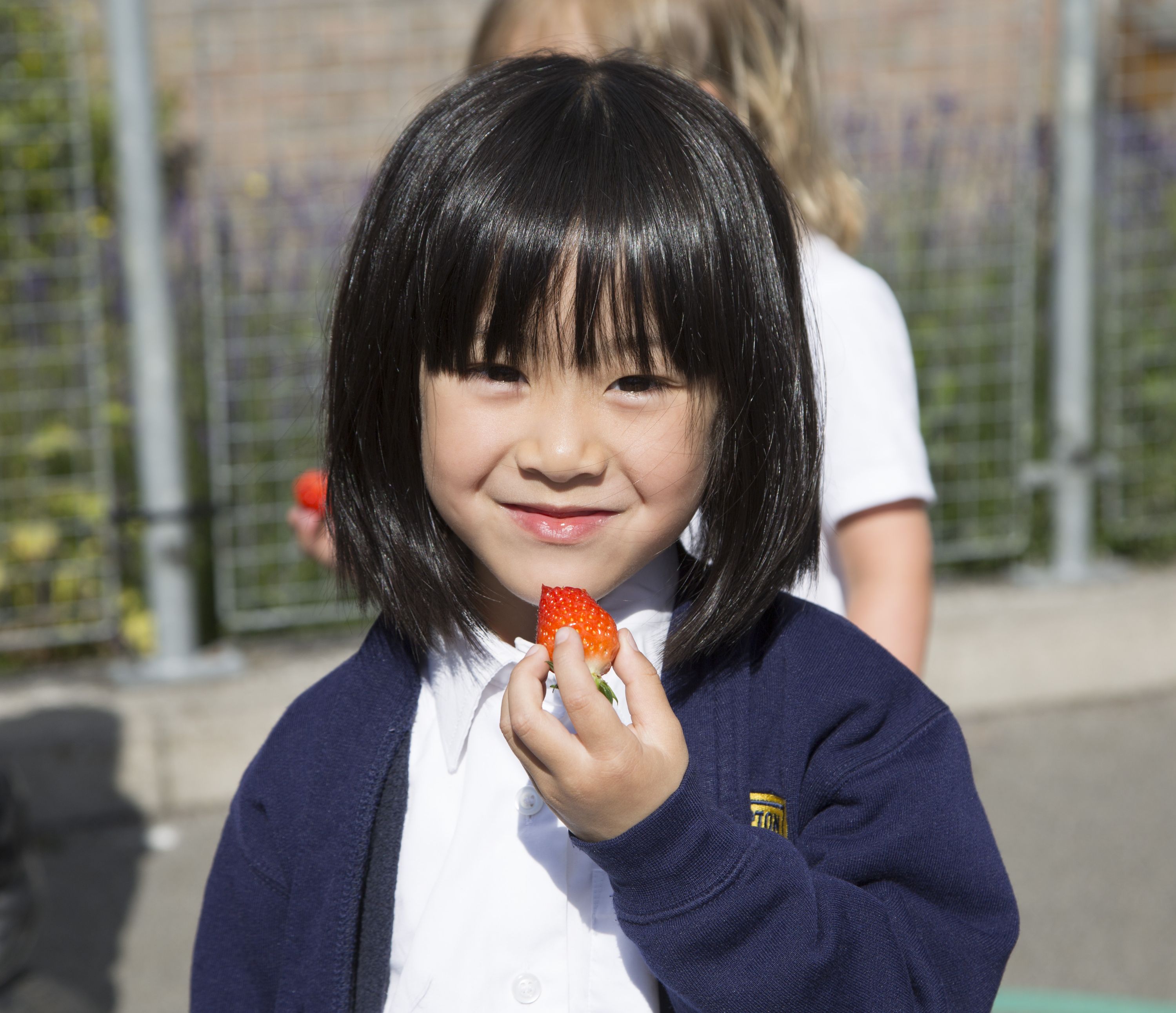 Smiling girls with a strawberry in her hand